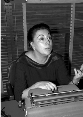 Rosario Castellanos conversa sentada tras un escritorio, retrato.png