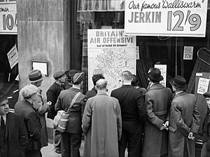 Archivo:A British airman is amongst a group of civilians crowded around the window of a shop in Holborn, London, to look at a map illustrating how the RAF is striking back at Germany during 1940. D1254
