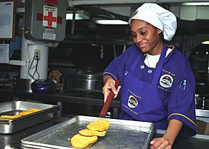 Archivo:US Navy 030418-N-9741A-007 Mess Management Specialist 3rd Class Stacey Davis from New York, N.Y. moves chicken patties from the baking pan to a serving dish