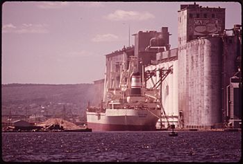 Archivo:SHIP LOADING AT THE CARGIL GRAIN ELEVATOR. GRAIN PARTICLES ESCAPE INTO THE AIR, SETTLE ON THE DOCK AND ON THE SURFACE... - NARA - 551582