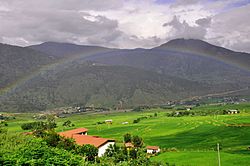 The households in the midst of green paddy field embraced by beautiful rainbow.JPG