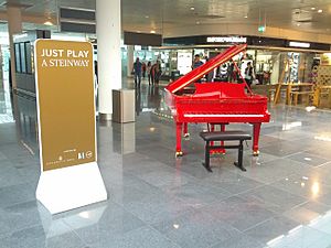 Archivo:Just Play a Steinway - Red public Steinway piano in Munich Airport terminal (2015-05-23 17.29.42 by Eric Fischer)