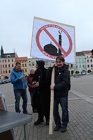Hombre con un cartel donde se muestra una mezquita con el signo de prohibición, durante las protestas contra la llegada de refugiados del mundo islámico a České Budějovice, República Checa (2015).