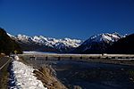 photo of a bridge over a river, with snow capped mountains in the background