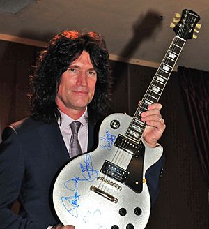 Archivo:Tommy Thayer without KISS makeup, holding up autographed guitar, 2013