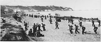Archivo:Near Algiers, "Torch" troops hit the beaches behind a large American flag "Left" hoping for the French Army not fire... - NARA - 195516