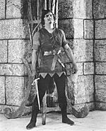 Archivo:Fairbanks Robin Hood standing by wall w sword