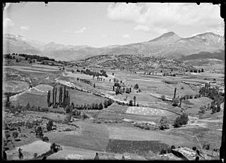 Turons amb camps i alguns arbres i muntanyes al fons, des de San Feliú de Veri.jpeg