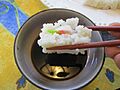 Showing how to dip a piece of sushi into a bowl of soy sauce