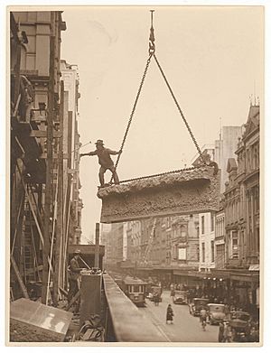 Archivo:Building labourer on a stone being hoisted up to building, Pitt St, Sydney, c. 1930s, by Sam Hood (4441498235)