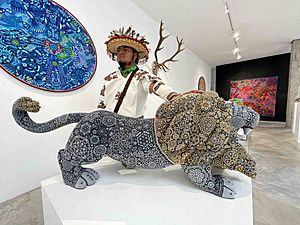 Archivo:Artista wixárika con escultura de león intervenida con arte tradicional en micro chaquira de cristal.
