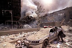 Archivo:Rescue worker reaching into a New York Police car covered with debris (28802606564)