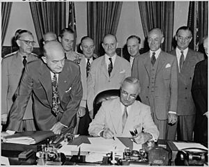 Archivo:Photograph of President Truman at his desk in the Oval Office, signing the National Security Act Amendments of 1949... - NARA - 200168