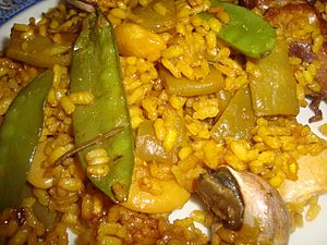 Archivo:Plato de paella de arroz con tirabeques y caracoles