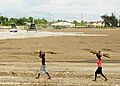 US Navy 100219-N-9643W-340 Haitian children carry sugarcane across a field as Sailors from Amphibious Construction Battalion (ACB) 2 clear land for a construction site