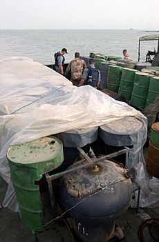 Archivo:US Navy 030321-N-4655M-029 Coalition Navy Explosive Ordnance Disposal (EOD) team members inspect camouflaged mines hidden inside oil barrels on the deck of an Iraqi shipping barge