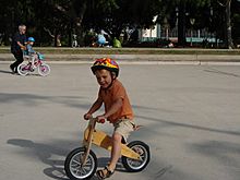 Archivo:Balance bike ridden solo and conventional bike ridden with help of adult