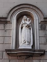 Imagen de una virgen con su hijo en brazo dentro de una hornacina en un muro exterior de un edificio