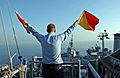 US Navy 051129-N-0685C-007 Quartermaster Seaman Ryan Ruona signals with semaphore flags during a replenishment at sea