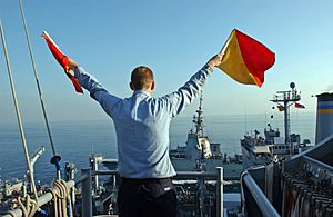 Archivo:US Navy 051129-N-0685C-007 Quartermaster Seaman Ryan Ruona signals with semaphore flags during a replenishment at sea