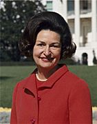 Lady Bird Johnson, photo portrait, standing at rear of White House, color, crop