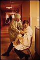A NEW FATHER HOLDS HIS CHILD FOR THE FIRST TIME IN LORETTO HOSPITAL IN NEW ULM, MINNESOTA. THERE ARE TWO HOSPITALS IN... - NARA - 558171