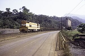 Archivo:ASC Leiden - F. van der Kraaij Collection - 13 - 008 - LAMCO J.V. Conveyor belt to silos. Locomotive nr. 303 with wagons loaded with iron ore - Yekepa, Nimba county, Liberia - 1976
