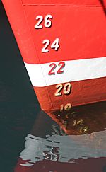 Archivo:Draft marks on a ship's bow, with reflections