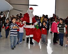 Archivo:US Navy 091212-N-6999T-005 Children from the Make-A-Wish Foundation escort Santa to his chair during their visit to Navy Air Squadron VR-57