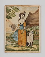 Imagen de una mujer de pie con vestido color naranja en un prado con una cabra detrás, la escena es de día