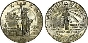 Archivo:Dollar américain de 1986, édition limitée représentant la statue de la liberté et le bâtiment principal d’Ellis Island,
