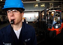 US Navy 060221-N-2984R-006 Seaman Joshua Macdonald blows a whistle to warn Sailors that forklifts are moving through the hangar bay aboard the Nimitz-class aircraft carrier USS Harry S. Truman (CVN 75)