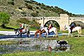 CRUZANDO EL RIO ALMONTE A CABALLO CON PUENTE MEDIEVAL AL FONDO