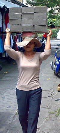 Archivo:Female laborer transporting concrete blocks in Bali-cropped